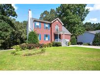 Charming two-story red brick home with blue shutters, surrounded by a lush green lawn and mature trees at 3161 Pagoda Trce, Lawrenceville, GA 30043