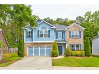 Charming two-story home with a blue exterior, brick accents, a well-manicured lawn, and a two-car garage at 133 Parkway Dr, Fairburn, GA 30213