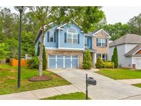 Charming two-story home boasts a well-manicured lawn, blue siding, and a two-car garage at 133 Parkway Dr, Fairburn, GA 30213