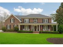 Charming brick home with a covered porch, well-manicured lawn, and inviting curb appeal at 210 Little River Farms Trl, Canton, GA 30115