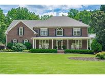 Charming brick home featuring a covered porch, manicured landscaping, and lush green lawn at 210 Little River Farms Trl, Canton, GA 30115