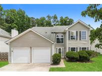 Charming two-story home with a two-car garage, green lawn, and manicured bushes at 2743 High Tide Dr, Atlanta, GA 30349