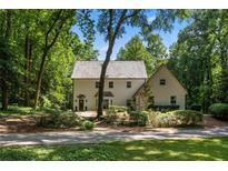 Inviting two-story home featuring a light-colored exterior, mature trees and a charming landscaped yard at 1260 Heards Ferry Rd, Sandy Springs, GA 30328