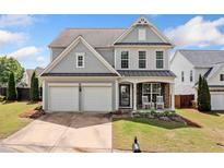 Charming two-story home featuring a two-car garage, covered porch with rocking chairs, and manicured lawn at 501 White Oak Path, Canton, GA 30115