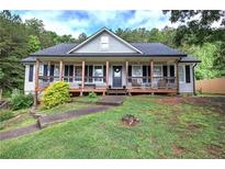 Charming home featuring a welcoming front porch, a well-maintained lawn, and mature trees at 527 Cass White Nw Rd, Cartersville, GA 30121