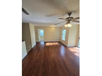 A spacious living room features hardwood floors, a ceiling fan and sliding door access to the exterior of the home at 1202 Santa Fe Pkwy, Atlanta, GA 30350