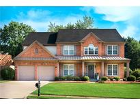 Charming brick home featuring a well-manicured lawn and a two-car garage at 5281 Tormeall Trce, Suwanee, GA 30024