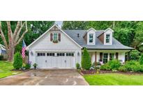 Charming two-story home with a white exterior, a 2-car garage, a manicured lawn, and an American flag at 115 Ocee View Ct, Alpharetta, GA 30022