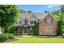 Beautiful two-story home featuring manicured landscaping, a mix of brick and stone, and a welcoming front porch at 5025 Savannah Run, Cumming, GA 30040