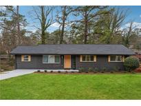Charming one-story home with a well-manicured lawn and newly painted dark gray exterior with wooden accents at 1667 Atherton Cir, Decatur, GA 30035