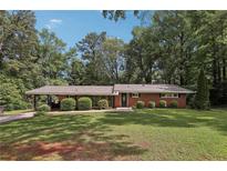 Charming one-story brick home with lush green lawn and mature trees offering great curb appeal at 112 Pioneer Trail, Cartersville, GA 30121