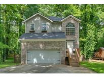 Charming two-story home features a brick facade, arched window, and a two-car garage nestled among mature trees at 2766 Stonecreek Se Rd, Smyrna, GA 30080