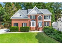 Charming two-story brick home with a manicured lawn, lush landscaping, and a welcoming light blue front door at 1265 Timberline Pl, Alpharetta, GA 30005