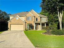Traditional brick two-story home with a manicured lawn and attached two-car garage in a suburban setting at 3200 Emma Marie Pl, Buford, GA 30519
