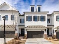 Charming two-story townhome boasts a painted brick facade, dark window shutters, and attached garage at 707 Dodd N Ln # 164, Buford, GA 30518