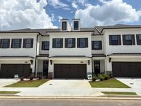 Beautiful new construction townhome with a white brick facade, dark trim and a two car garage at 707 Dodd N Ln # 164, Buford, GA 30518