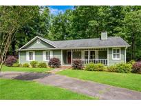 Charming ranch home featuring a covered front porch, green siding, white shutters, and lush landscaping at 789 Concord Sw Rd, Smyrna, GA 30082