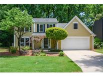 Charming home features a manicured lawn, mature trees, and a two-car garage at 9050 Brockham Way, Alpharetta, GA 30022