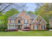 Charming two-story brick home with manicured lawn, black shutters, and welcoming front porch at 710 Bentgrass Ct, Dacula, GA 30019