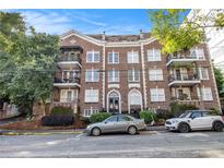 Classic brick apartment building featuring wrought iron balconies and arched doorway with lush landscaping at 61 16Th Ne St # 4, Atlanta, GA 30309