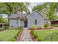 Charming blue home with a well-manicured front yard, stone pathway and black-framed glass front door at 1143 Church Nw St, Atlanta, GA 30318