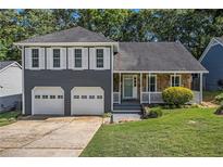 Charming two-story home featuring a stone facade, gray siding, shutters, a well-manicured lawn, and a two-car garage at 4865 Fenbrook Dr, Stone Mountain, GA 30088