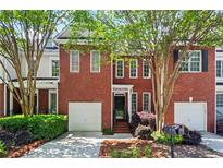 Beautiful brick townhome featuring an attached garage and professionally landscaped front yard at 4910 Longcourt Se Trce # 13, Atlanta, GA 30339