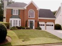 Charming two-story brick home featuring a well-manicured lawn, arched window and two-car garage at 1414 Justin Dr, Lawrenceville, GA 30043