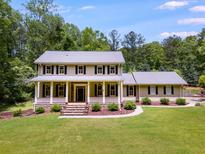Charming two-story home with a covered front porch and well-manicured lawn, surrounded by lush trees at 7720 Milam Rd, Winston, GA 30187