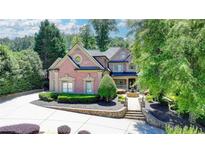 Stunning brick home featuring lush landscaping, fountain, and a circular driveway at 8525 Saint Marlo Fairway Way, Duluth, GA 30097