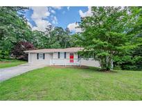 Charming single-story home featuring a well-manicured lawn, a red door, and a cozy front porch at 3920 Stonewall Tell Rd, Atlanta, GA 30349