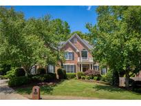 Charming two-story brick home with lush landscaping, mature trees, and a small balcony, creating a welcoming curb appeal at 935 Brookline Way, Alpharetta, GA 30022
