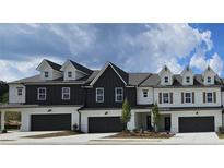 Modern townhomes featuring painted brick, dark trim, dormer windows, and individual garages, all under a cloudy sky at 210 Sharon Ln, Loganville, GA 30052