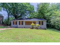 Modest home featuring a front yard with grass, a small covered entryway, and boarded-up windows at 1906 Oak Valley Rd, Decatur, GA 30035