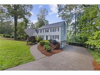 Charming two-story home with a landscaped yard and a curved driveway nestled among mature trees at 4468 Windsor Oaks Dr, Marietta, GA 30066