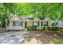 Charming yellow home featuring a well-kept lawn and mature shade trees creating curb appeal at 6185 Marbut Farms, Lithonia, GA 30058