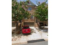 Brick townhouse with two-car garage and a beautiful, blooming Crape Myrtle in the front yard at 1547 Cambridge Pl, Marietta, GA 30062