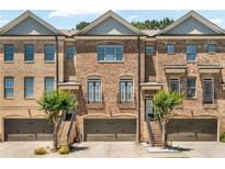 Brick townhome featuring a two-car garage and manicured landscaping at 1547 Cambridge Pl, Marietta, GA 30062
