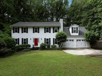 Charming two-story home with white siding, black shutters, red door, well-manicured lawn, and an attached two-car garage at 517 Sheritan Sw Way, Smyrna, GA 30082