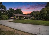 Charming single-story home with lush lawn and a long drive surrounded by mature trees at dusk at 2452 Camp Mitchell Rd, Grayson, GA 30017