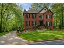Beautiful brick home featuring mature landscaping, a manicured lawn, and a long driveway leading up to the house at 421 Congress Pkwy, Lawrenceville, GA 30044