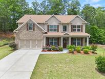 Charming two-story home featuring a manicured lawn and a welcoming front porch with beautiful flowerbeds at 871 Wisteria View Ct, Dacula, GA 30019