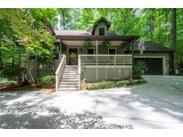 Charming home featuring a covered porch, attached garage, and inviting curb appeal with mature trees at 1560 Bubbling Creek Ne Rd, Atlanta, GA 30319