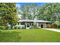 Charming brick home with a well-manicured lawn and covered carport, complemented by mature trees and landscaping at 233 Dorris Sw Dr, Marietta, GA 30060