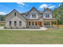 Stunning two-story home featuring a brick facade, covered porch with wooden beams, and professionally landscaped front yard at 1461 Leach Dr, Lawrenceville, GA 30045