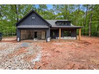 Modern farmhouse exterior with a dark gray facade, open garage, and inviting covered porch with timber columns at 1687 Harmony Rd, Temple, GA 30179