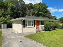 Charming one-story home featuring a well-manicured lawn, a painted brick exterior, and a welcoming orange front door at 3593 Adkins Nw Rd, Atlanta, GA 30331