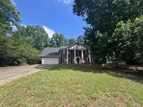 Two-story brick home with white columns, inviting entrance, and lush surrounding greenery at 2000 Brickton Sta, Buford, GA 30518