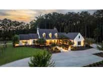 Stunning country home featuring manicured landscaping and a circular driveway at sunset at 7255 Old Rico Rd, Chattahoochee Hills, GA 30268