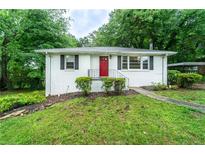 Charming single-story home with a red front door, white brick, and lush landscaping at 218 Woodview Se Ln, Smyrna, GA 30082